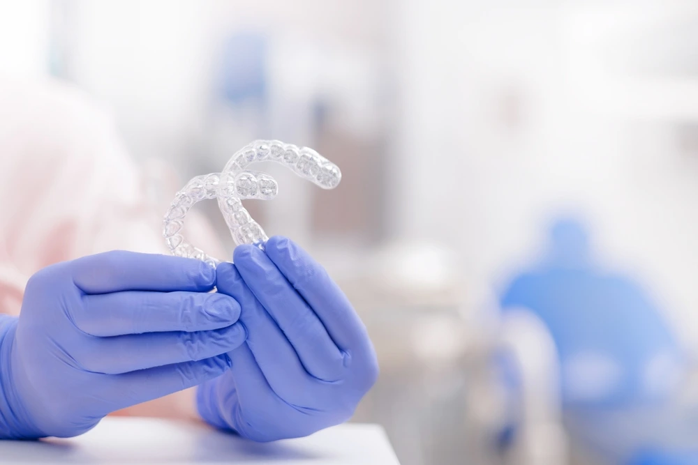 Gloved hands holding a set of invisible clear aligners. Professional orthodontic treatments at St Leonards Green Dental.